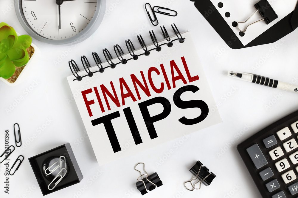 FINANCIAL TIPS. text on white notepad paper on light background near calculator, plant, table clock.